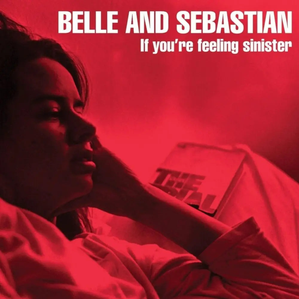 A red-tinted album cover featuring a person resting their head on their hand, with a book titled ’The Trial’ in the background.